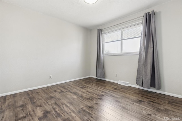 spare room with dark hardwood / wood-style flooring and a textured ceiling