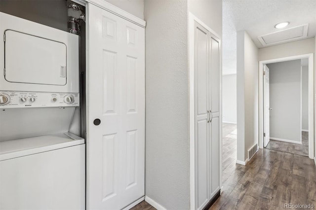 laundry area featuring stacked washer and dryer and dark hardwood / wood-style floors