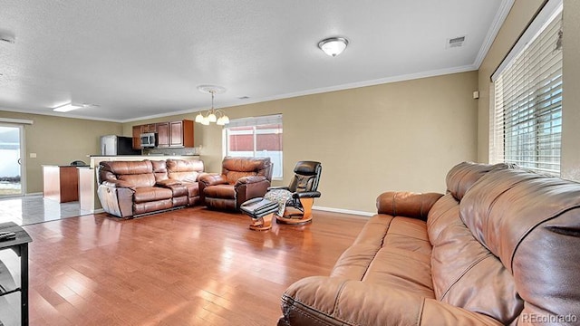 living room with crown molding, a chandelier, a textured ceiling, and light wood-type flooring