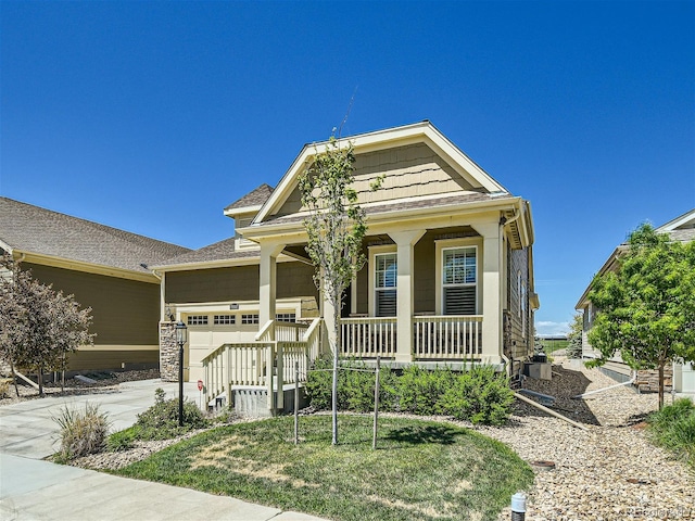 view of front of home with a garage, covered porch, and a front lawn