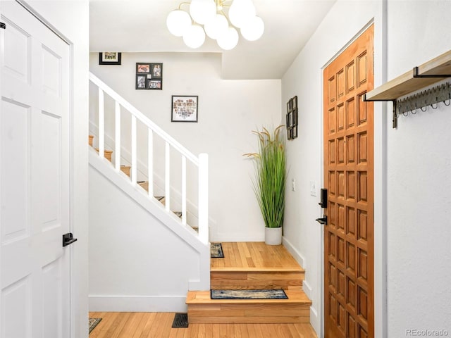 entryway with stairs, hardwood / wood-style floors, a chandelier, and baseboards