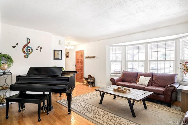 living room featuring a textured ceiling, baseboards, and light wood-style floors