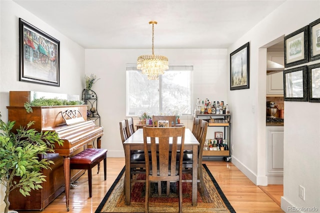 dining space featuring light wood-style floors, baseboards, and an inviting chandelier