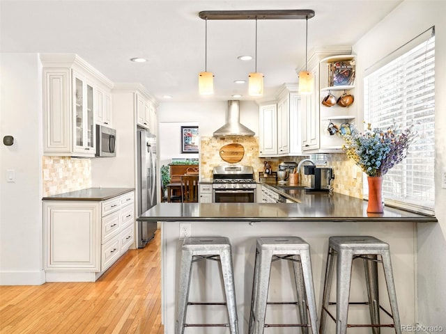 kitchen featuring appliances with stainless steel finishes, dark countertops, pendant lighting, and a breakfast bar area