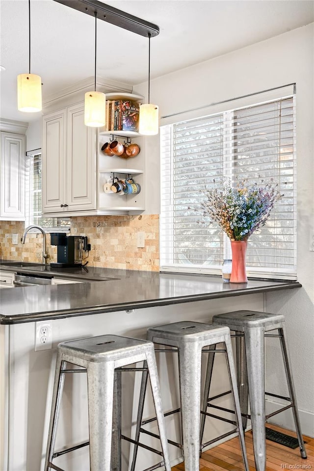 kitchen with a breakfast bar, dark countertops, and pendant lighting