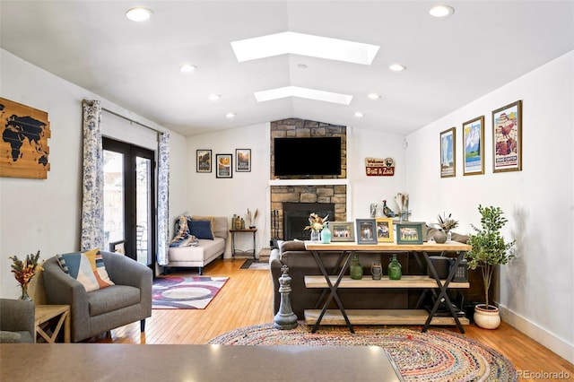 living room with recessed lighting, a fireplace, wood finished floors, french doors, and lofted ceiling with skylight