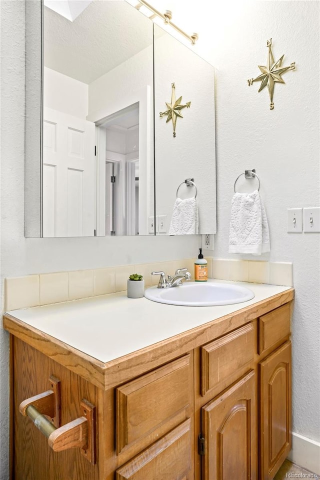 bathroom with a textured wall and vanity