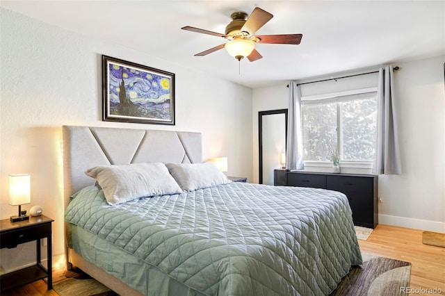 bedroom featuring wood finished floors, a ceiling fan, and baseboards