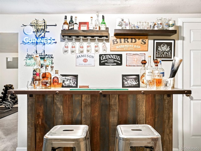 bar with a textured ceiling and a dry bar