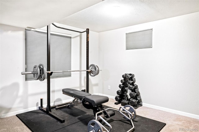 exercise area with a textured ceiling, carpet floors, and baseboards