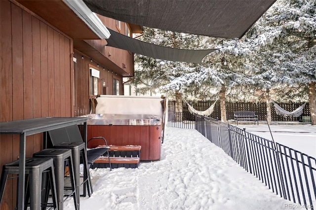 snowy yard featuring a fenced backyard and a hot tub