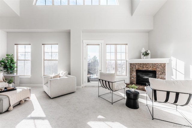 living room with light carpet, a towering ceiling, and a premium fireplace