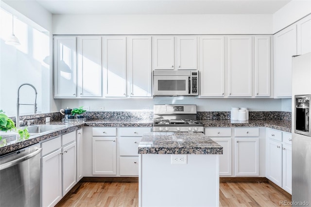 kitchen with sink, light hardwood / wood-style flooring, appliances with stainless steel finishes, white cabinets, and a kitchen island