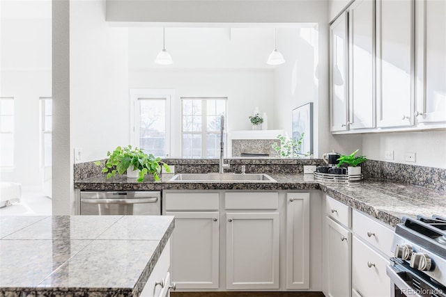 kitchen featuring hanging light fixtures, appliances with stainless steel finishes, sink, and white cabinets