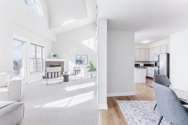 dining area featuring a towering ceiling, a healthy amount of sunlight, and light hardwood / wood-style flooring