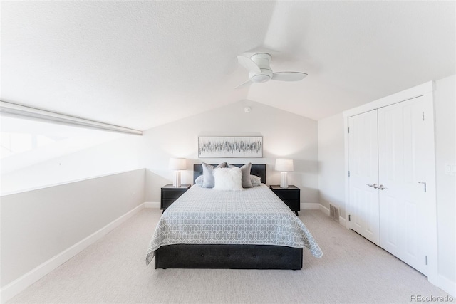 carpeted bedroom with ceiling fan, lofted ceiling, and a closet