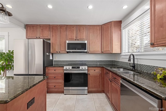 kitchen featuring sink, tasteful backsplash, light tile patterned floors, dark stone countertops, and appliances with stainless steel finishes