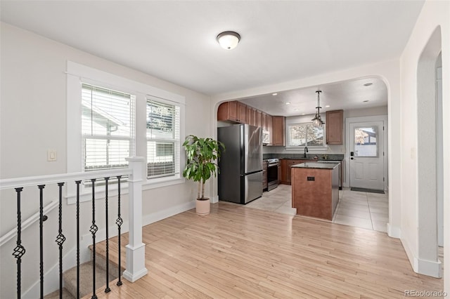 kitchen with decorative light fixtures, a wealth of natural light, stainless steel appliances, and a kitchen island