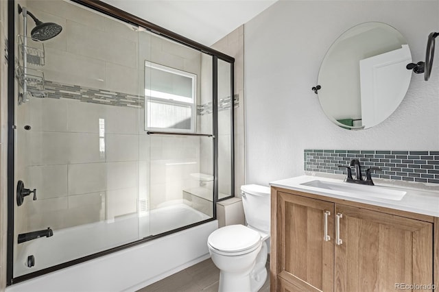 full bathroom with tasteful backsplash, vanity, combined bath / shower with glass door, and toilet