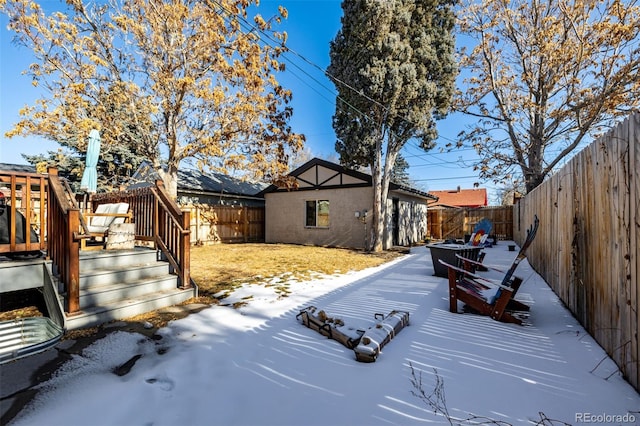 yard layered in snow featuring an outbuilding and a deck