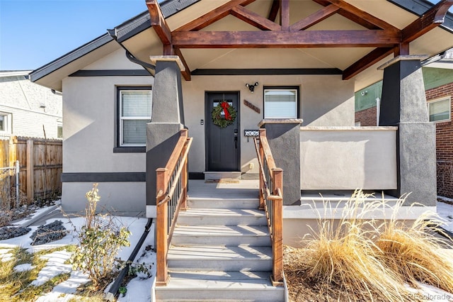 entrance to property with fence and stucco siding