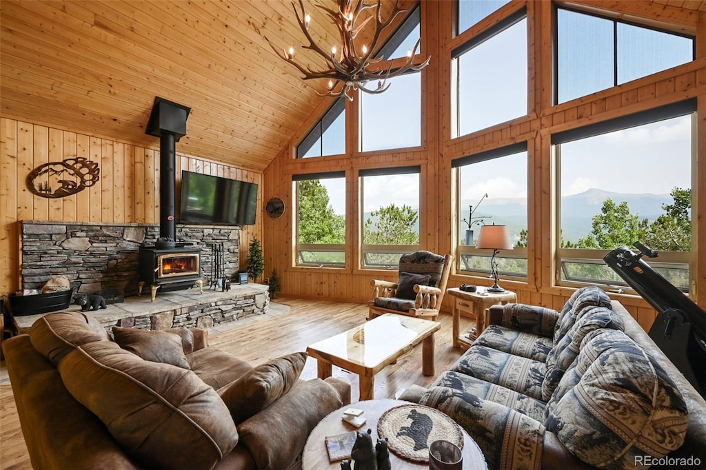 living room with a chandelier, wood ceiling, a wood stove, high vaulted ceiling, and light wood-type flooring