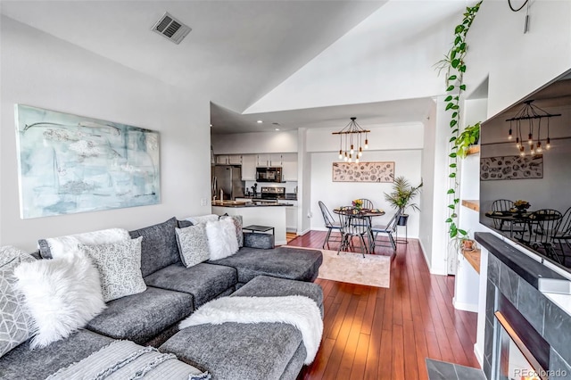 living room featuring a chandelier, dark wood-style floors, and vaulted ceiling