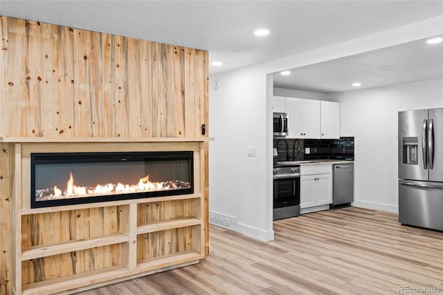 kitchen with light wood finished floors, visible vents, decorative backsplash, appliances with stainless steel finishes, and white cabinets