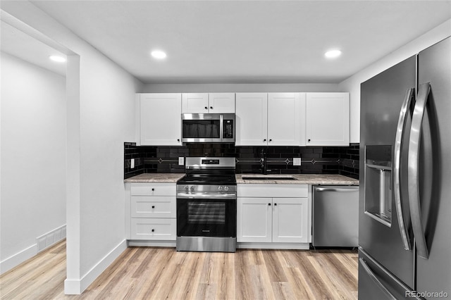 kitchen with light stone counters, a sink, visible vents, white cabinetry, and appliances with stainless steel finishes