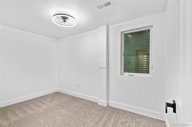 carpeted spare room featuring a textured ceiling, visible vents, and baseboards