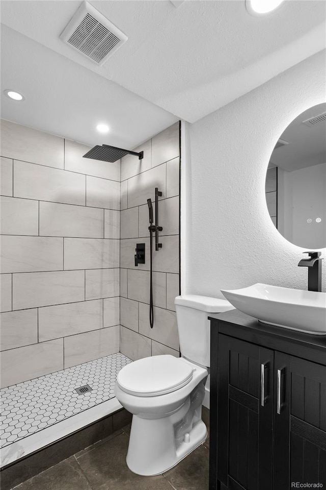 full bathroom featuring toilet, vanity, visible vents, and a shower stall