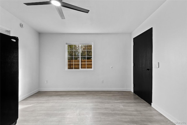 empty room featuring ceiling fan, light wood-type flooring, and baseboards