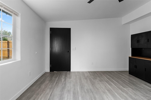 interior space featuring ceiling fan, light wood-style flooring, and baseboards