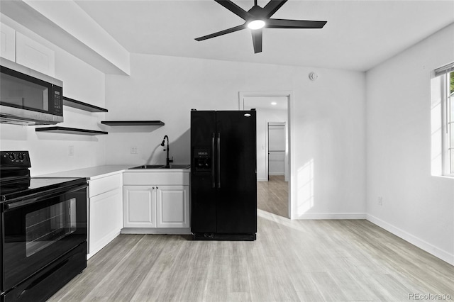 kitchen with white cabinets, light wood-style flooring, light countertops, black appliances, and a sink