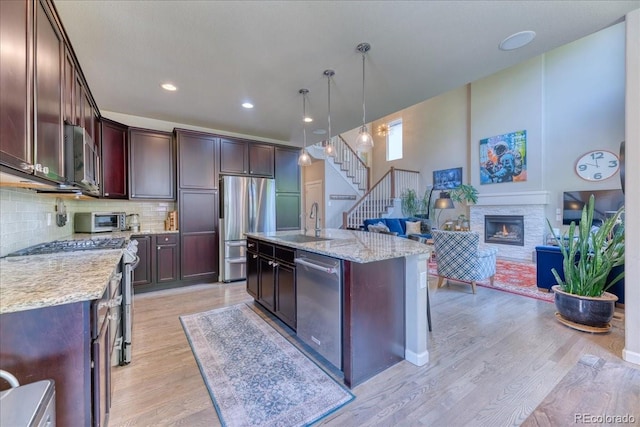2347 S Loveland St, Lakewood, CO 80228 - kitchen with appliances with stainless steel finishes, a glass covered fireplace, tasteful backsplash, light wood-style floors, and a sink