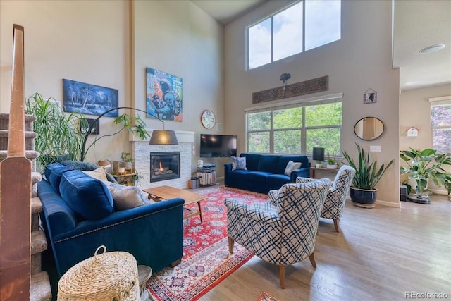 2347 S Loveland St, Lakewood, CO 80228 - living area with wood finished floors, a stone fireplace, a high ceiling, and baseboards