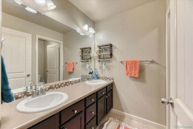 2347 S Loveland St, Lakewood, CO 80228 - full bathroom with toilet, double vanity, tile patterned flooring, baseboards, and a textured wall
