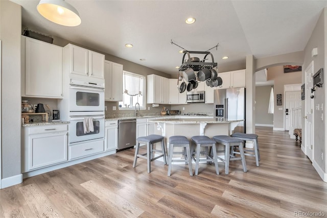 10695 Wynspire Rd, Highlands Ranch, CO 80130 - kitchen featuring appliances with stainless steel finishes, a breakfast bar, arched walkways, a kitchen island, and recessed lighting