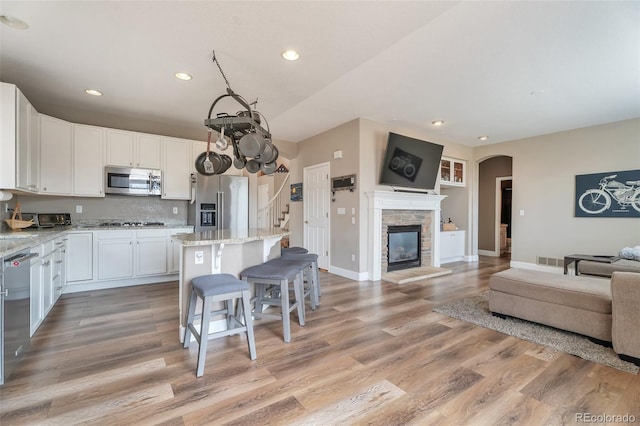 10695 Wynspire Rd, Highlands Ranch, CO 80130 - kitchen featuring appliances with stainless steel finishes, open floor plan, recessed lighting, a breakfast bar, and white cabinets