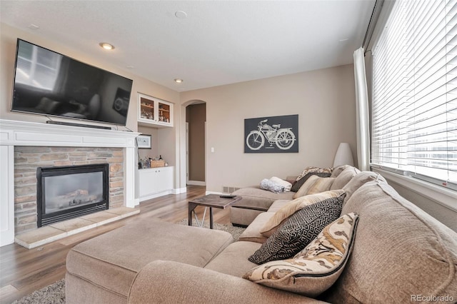 10695 Wynspire Rd, Highlands Ranch, CO 80130 - living area featuring arched walkways, a stone fireplace, wood finished floors, recessed lighting, and baseboards