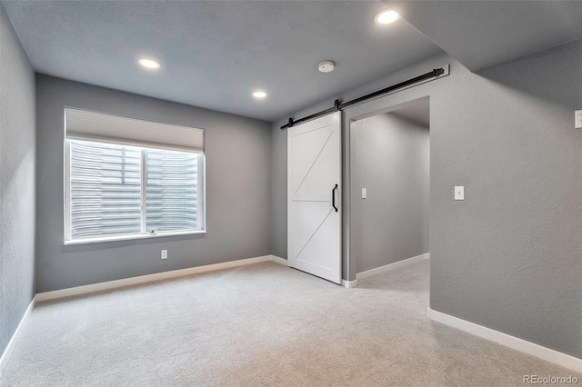 10695 Wynspire Rd, Highlands Ranch, CO 80130 - unfurnished bedroom with a barn door, light colored carpet, baseboards, and recessed lighting