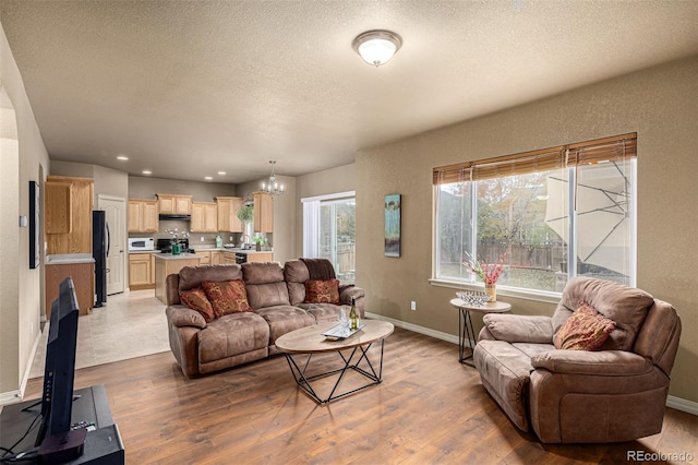 living room with hardwood / wood-style floors, a notable chandelier, and a textured ceiling