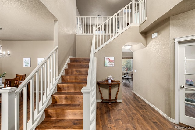 stairway featuring hardwood / wood-style flooring, a textured ceiling, and an inviting chandelier