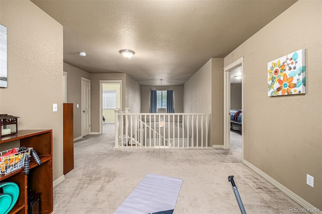 corridor featuring light colored carpet and a textured ceiling