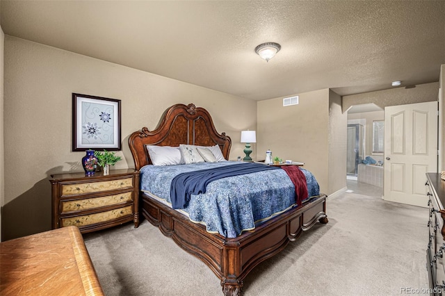 bedroom featuring ensuite bath, carpet flooring, and a textured ceiling