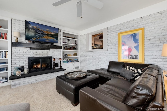 10220 W Montgomery Ave, Littleton, CO 80127 - carpeted living room featuring built in shelves, a fireplace, a ceiling fan, and brick wall