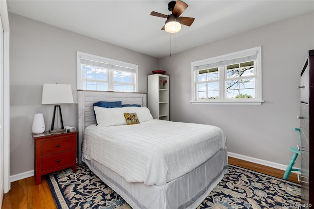 10220 W Montgomery Ave, Littleton, CO 80127 - bedroom with multiple windows, baseboards, wood finished floors, and a ceiling fan