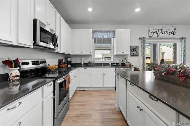 kitchen with sink, white cabinetry, light hardwood / wood-style flooring, and stainless steel appliances