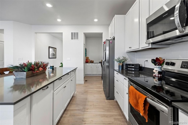 kitchen featuring light wood-type flooring, appliances with stainless steel finishes, and white cabinetry