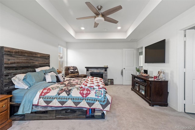 carpeted bedroom featuring ceiling fan and a tray ceiling